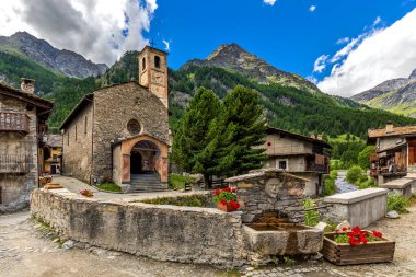 Piedmont, İtalya 'daki küçük bir dağ köyü olan Chianale' de mavi gökyüzü altında eski kilise ve evler..