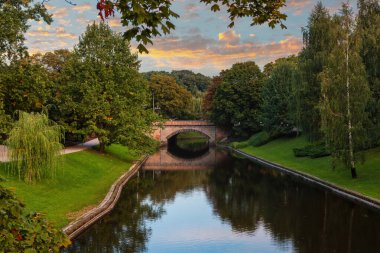 Letonya 'nın Riga kentindeki ağaçlar arasındaki su kanalı ve köprü manzarası.