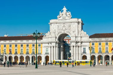LISBON, PORTUGAL - 16 HAZİRAN 2017: Mavi gökyüzünün altındaki ünlü Rua Augusta Kemeri, sarı tramvay ve Lizbon 'daki Praca do Comercio' daki (Ticaret Meydanı) insanlar - Portekiz 'in başkenti, ünlü seyahat beldesi.
