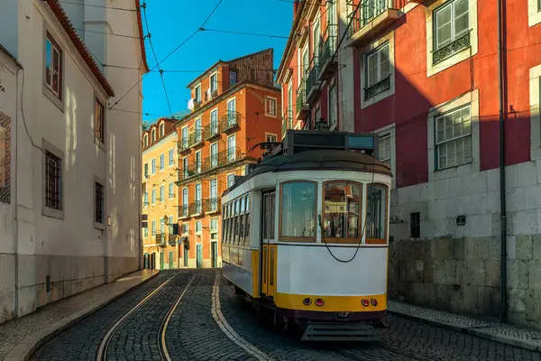Portekiz, Lizbon 'daki renkli binalar arasında dar bir kaldırım taşı caddesinde ikonik klasik tramvay.