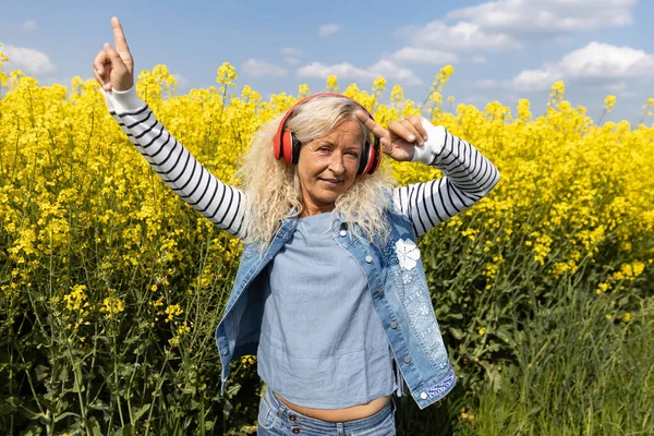 Mujer Mayor Escuchar Música Con Auriculares Campo Canola Floreciente — Foto de Stock