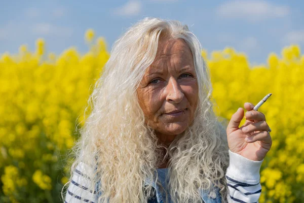 Elderly Woman Smoke Cigarette Rape Field Yellow Blossums — 스톡 사진