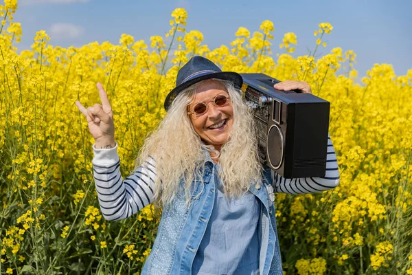 Elderly Woman have fun with vintage Boom Box in Nature.