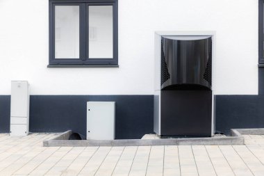 Yeni bir binanın ön cephesinde modern ısı pompası