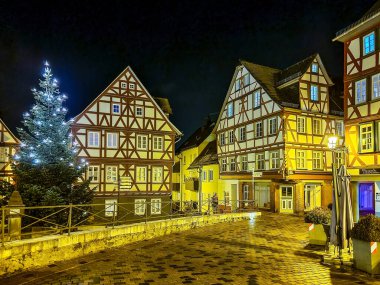 Wetzlar şehir merkezindeki halka açık bir alanda yarı ahşap bir ev ve aydınlatılmış noel ağacı olan gece sahnesi..