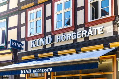 QUEDLINBURG, GERMANY - September 6, 2023:  KIND HRGERTE sign of the company Kind, specialized store for hearing aids and glasses in the old town of Quedlinburg in Germany.. clipart
