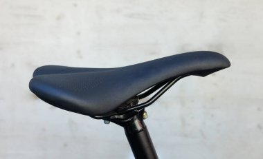 Parlak bir duvarın arkasında siyah bir bisiklet eyerinin ayrıntıları.