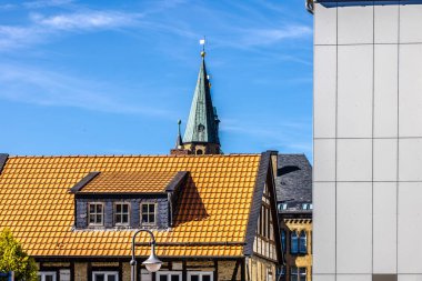 Geleneksel ve modern ev cepheleri ve kilise kulesi - Alman şehrinde kontrastlı mimari konsepti Goslar.