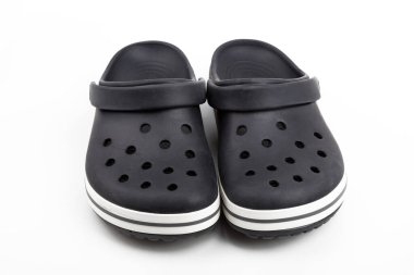 Beyaz arka planda izole edilmiş siyah plastik ayakkabılar giyiyorlar.