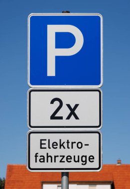 Mavi gökyüzünde şarj etmeye hazır iki elektrikli araç için park tabelası.