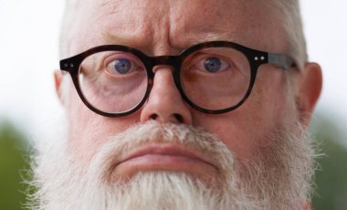 Üzgün ve hayal kırıklığına uğramış gözlüklü ve sakallı yaşlı adam kameraya bakıyor..