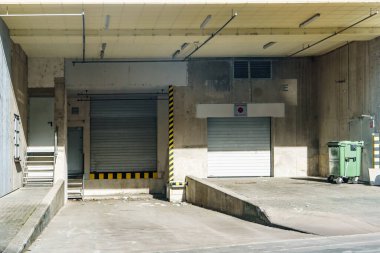 Kapalı kapaklı boş yükleme rıhtımları bir depoda kamyonları ve teslimatı bekliyor.