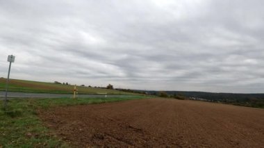 Altı görüntüde tarlalar, bir köy yolu ve bulutlu bir gökyüzü görünüyor.