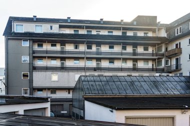 Bulutlu bir günde çok sayıda balkon ve pencerenin bulunduğu apartman cephesi