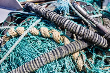 Yıpranmış halat ve şamandıralarla birbirine dolanmış canlı turkuaz balık ağı, deniz yaşamının dokularını ve renklerini gözler önüne seriyor.