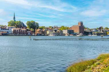 Kappeln, Almanya 'nın şehir manzarası, renkli binalar, kilise kulesi ve liman mavi gökyüzü altında nehir schlei' nin sakin sularını yansıtıyor.