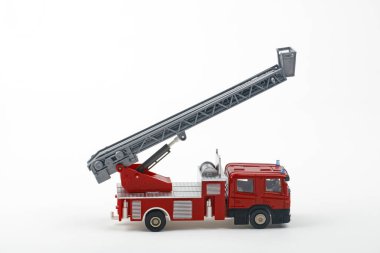 Merdiveni genişleten kırmızı ve gri oyuncak itfaiye aracı, beyaz arka planda izole edilmiş, oyun zamanı veya eğitim amaçlı olarak hazır..