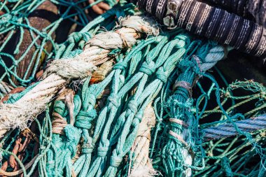 Yıpranmış halat ve şamandıralarla birbirine dolanmış canlı turkuaz balık ağı, deniz yaşamının dokularını ve renklerini gözler önüne seriyor.