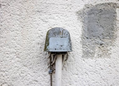 Telefon için eski, yıpranmış bir elektrik bağlantı kutusuna yakın plan beyaz dokulu bir duvara bağlı.