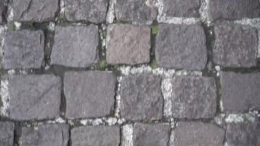 Yakından bakınca, yeşil ayakkabılar ve kot pantolon giyen adamların kaldırımda yürürken geride kaldığını görüyoruz.