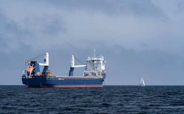 Kocaman bir kargo gemisi ve açık denizde küçük bir yelkenli. Macera, özgürlük ve irade kavramı. Yüksek kalite fotoğraf