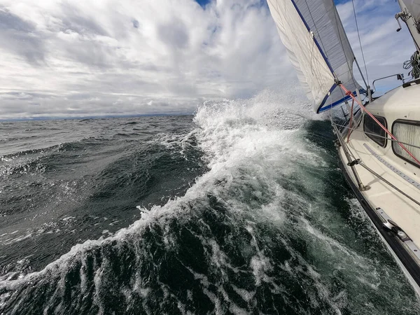Sailboat fights storm and waves in open sea. Concept of travel, adventure, risk and adrenaline.