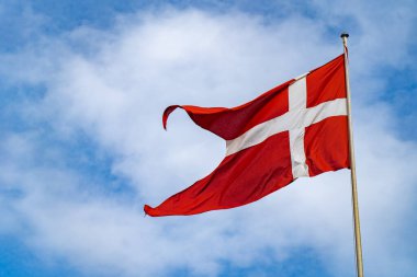 Mavi gökyüzünde bulutlarla izole edilmiş Danimarka bayrağı. Danimarka bayrağını yakın çekimde salla