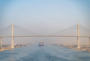 Huge cargo ships under Al Salam Bridge navigate by Suez Canal. Concept of transportation and logistics. clipart