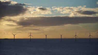 Gün batımında açık denizde rüzgar çiftliği. Offshore rüzgar jeneratörleri. Sürdürülebilir ve temiz enerji kavramı