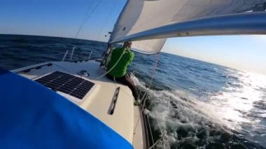 Young sailor managing sails on Sailboat in open, rough and wavy sea. adrenaline, adventure concept.