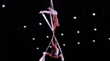Beyaz kostümlü sirk sanatçısının hava ipek ikilisi sahne arkasında performans sergiliyor. Yüksek kaliteli FullHD görüntüler