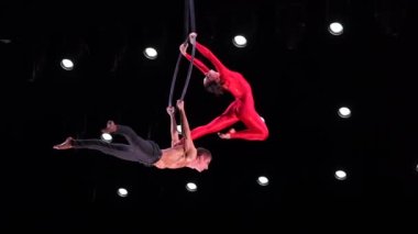 Siyah arkaplandaki hava çemberi ikilisi yavaş çekimde performans sergiliyor. Çiftte romantik ilişki kavramı.