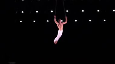 Siyah sahne arka planında Aerial kayışları üzerinde erkek, kaslı akrobat ağır çekimde jimnastik yapıyor. İrade, motivasyon ve tutku kavramı.