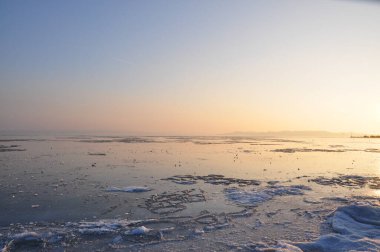 An icebound lake is his ice under the setting sun. clipart