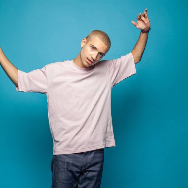Young handsome man standing against bright blue wall background