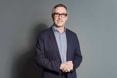 Gri arka planda gülümseyen orta yaşlı bir adam