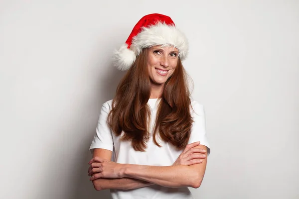 白い壁のスタジオの背景にクリスマスの帽子で幸せな笑顔の女性の肖像画 — ストック写真