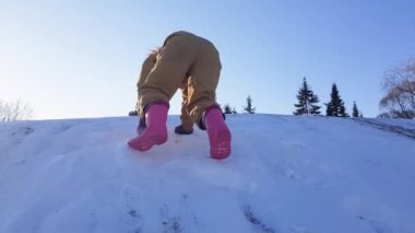 Çocuk kar dağının tepesine tırmanıyor.