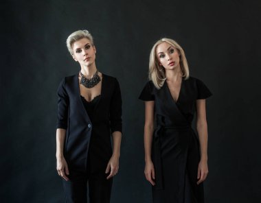 Two beautiful women are standing on black background