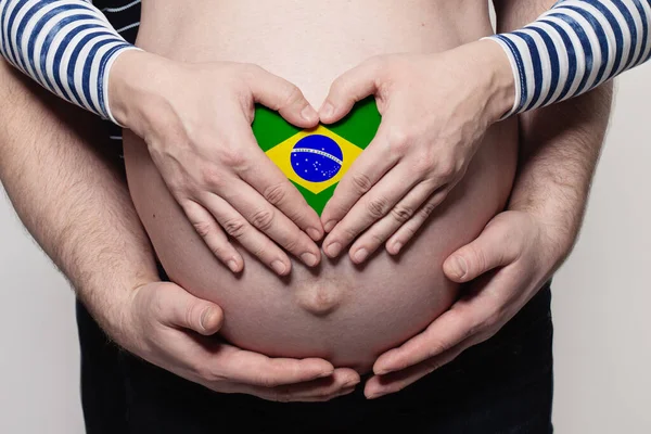 巴西家庭概念 男子抱着身披巴西国旗的孕妇的肚子和心脏进行特写 — 图库照片