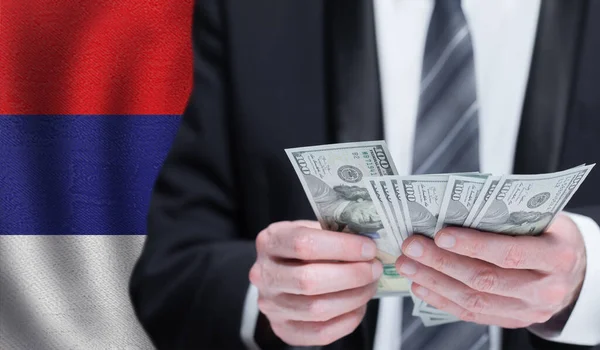 stock image Hands holding dollar money on flag of Serbia