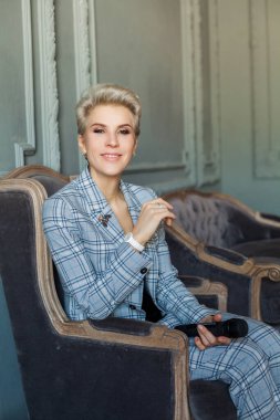 Güzel kadın gazeteci. Kanepede oturmuş mikrofon tutuyor.