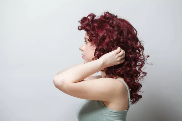 Belle Femme Touchant Ses Cheveux Bouclés Rouges Sur Fond Mur — Photo