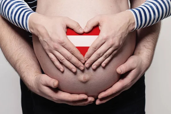 奥地利家庭概念 男子抱着身披奥地利国旗的孕妇的肚子和心脏进行特写 — 图库照片