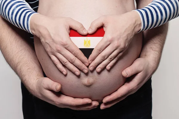 埃及家庭概念 男人抱着孕妇的肚子和心脏与埃及国旗的颜色特写 — 图库照片