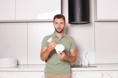 Portrait of man cleaning kitchen and holding sptay bottle with blank label for advertising