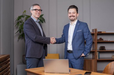 Takım elbiseli iki başarılı işadamı anlaşma yaptılar, anlaşma sağlandı.