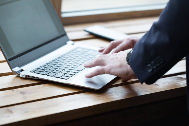 Businessman hands typing on laptop keyboard close up on the table