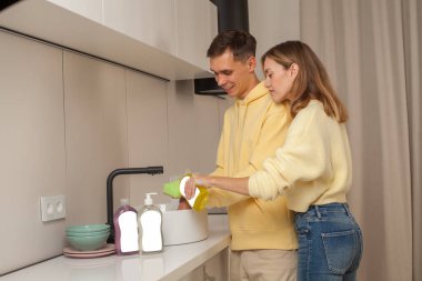Couple washing the dishes using dishwashing liquid with blank label