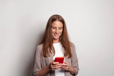 Optimistic happy smiling woman using smart phone against white studio wall banner background